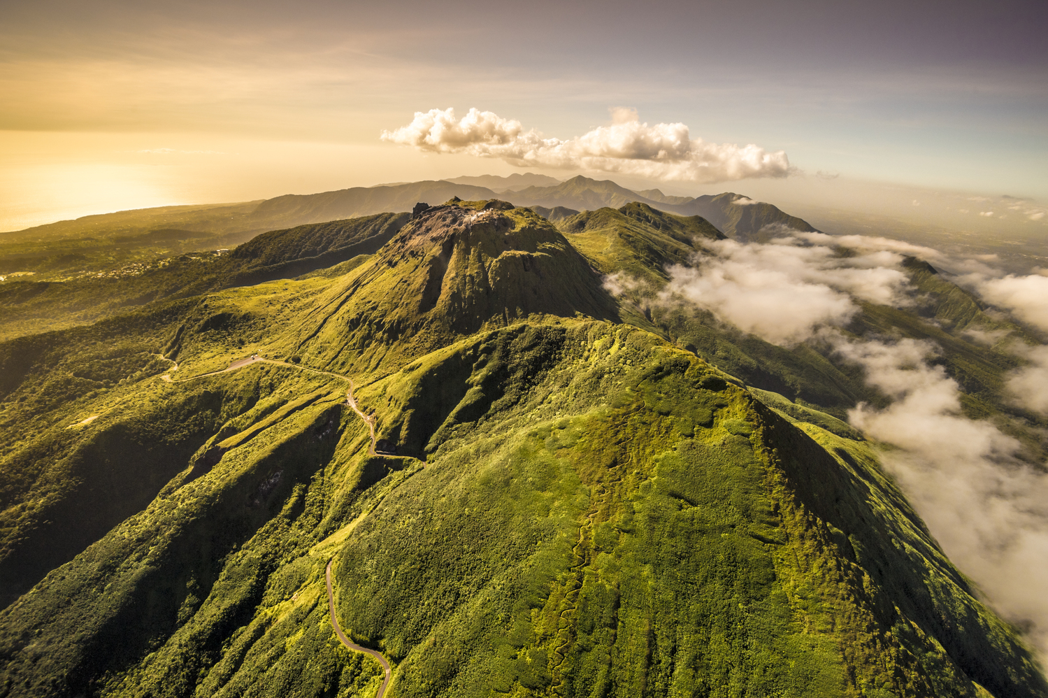 France, Guadeloupe, Basse-Terre, Saint-Claude, Vue aérienne Sud-Nord du sommet dégagé de la Soufrière, l'Échelle et toute la chaîne volcanique, visibles ensemble quelques jours par an seulement, ici en surplomb de La Citerne. Surnommée « vié madanm la » en créole guadeloupéen ou « la vieille dame » en français, est un volcan en activité situé dans le parc national. Seul volcan actif de l’île, actuellement à l’état de repos éruptif, elle fait partie d’un ensemble volcanique composé des volcans Carmichaël, le Nez Cassé, l’Échelle, la Citerne et la Madeleine. C'est l’un des neuf volcans actifs des Petites Antilles. La végétation sur les flancs de la Soufrière est remarquable pour sa biodiversité. Elle s'étage sur trois niveaux : la forêt tropicale dense jusqu'à 1 100 mètres, les maquis humides denses entre 1 100 et 1 400 mètres composés d'arbustes ne dépassant pas deux mètres de hauteur (entre autres, Schefflera attenuata, Clusia mangle, Miconia coriacea), les prairies sommitales d'où émergent des bromeliaceae : Guzmania plumieri omniprésent, et surtout Pitcairnia bifrons, espèce pionnière présente jusqu'au bord des bouches éruptives (PR) // France, Guadeloupe, Basse-Terre, Saint-Claude, Aerial View South-North summit free of La Soufrière, L'Échelle and all the volcanic chain, visible together only a few days a year, here overlooking La Citerne. Nicknamed "the vié madanm" in Guadeloupean Creole or "the old lady" in French, La Soufrière is an active volcano located in the national park. Only active volcano on the island, currently the eruptive resting state, it is part of a volcanic ensemble of Carmichael volcanoes, Nose Broken, Scale, Cistern and the Madeleine. This is one of the nine active volcanoes of the Lesser Antilles. The vegetation on the slopes of La Soufrière is noted for its biodiversity. It sprawls over three levels: the dense tropical forest to 1100 meters, dense humid scrub between 1100 and 1400 m